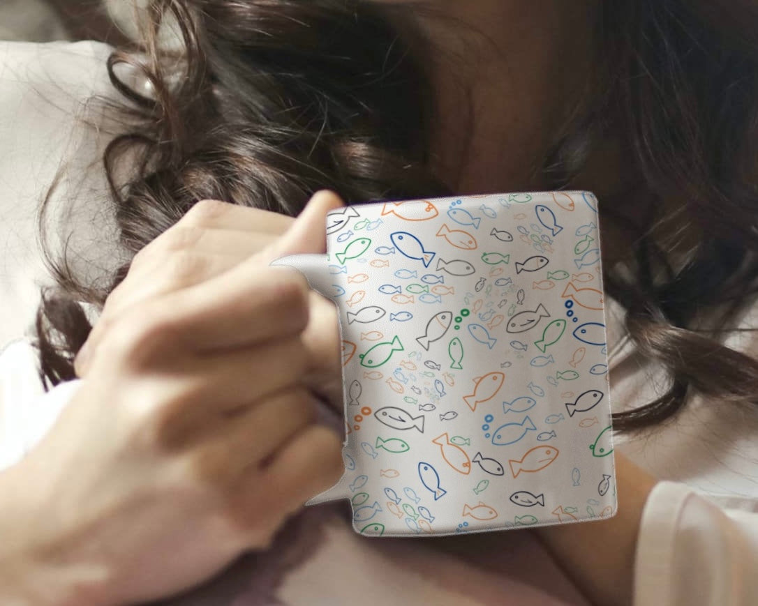 Person holding a mug with a fish pattern
