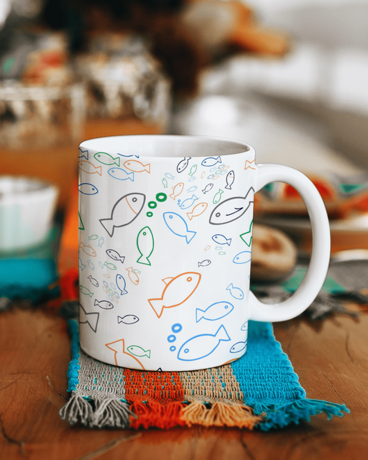 White mug with fish pattern on a colorful fabric coaster
