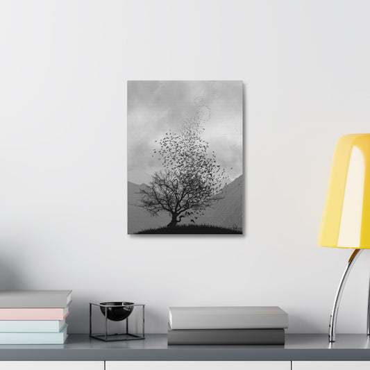 Framed black and white tree artwork on a wall above a desk with books and a lamp.